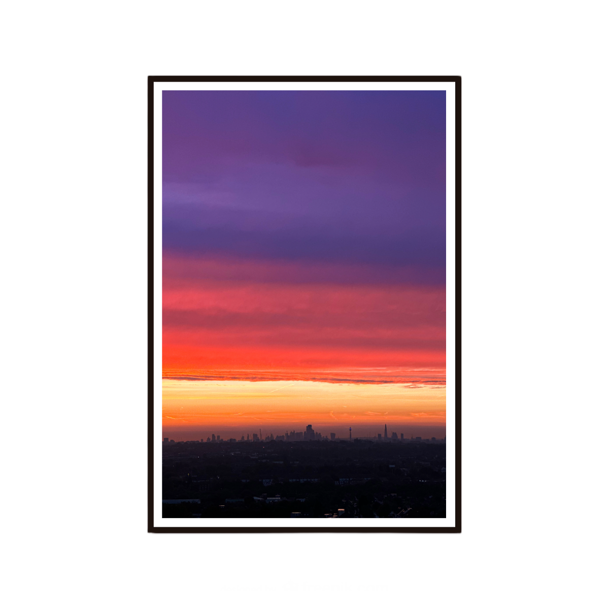Framed artwork of a city skyline at sunset with a gradient sky from purple to orange.