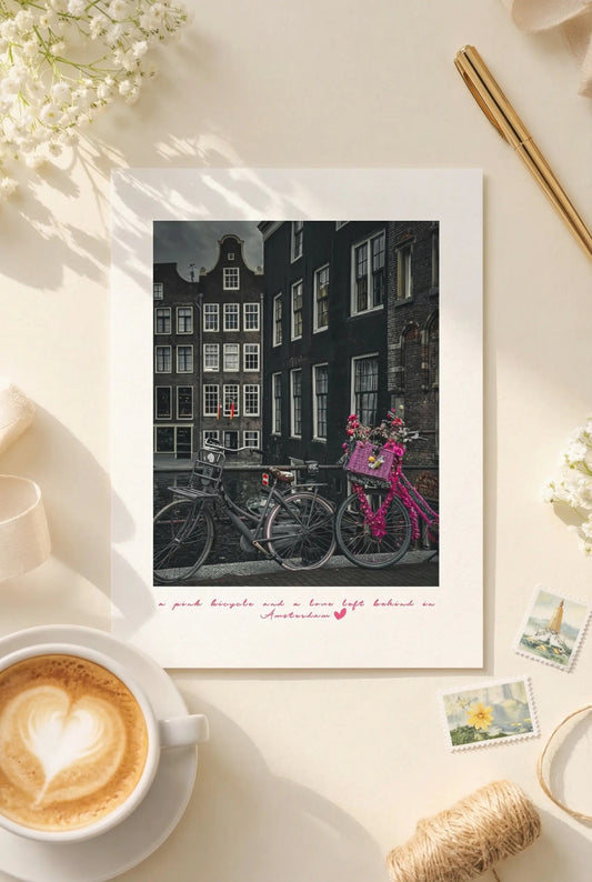 Amsterdam postcard featuring a vintage pink bicycle beside canal houses.